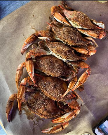 A pile of seasoned cooked crabs on brown paper.