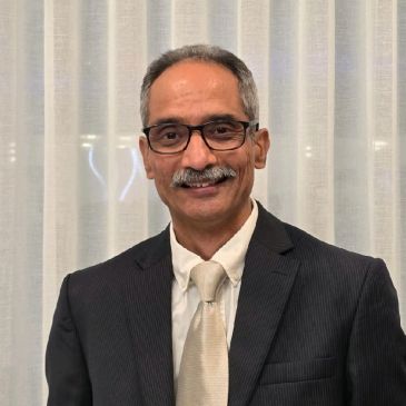 Man in a suit and tie smiling at the camera.