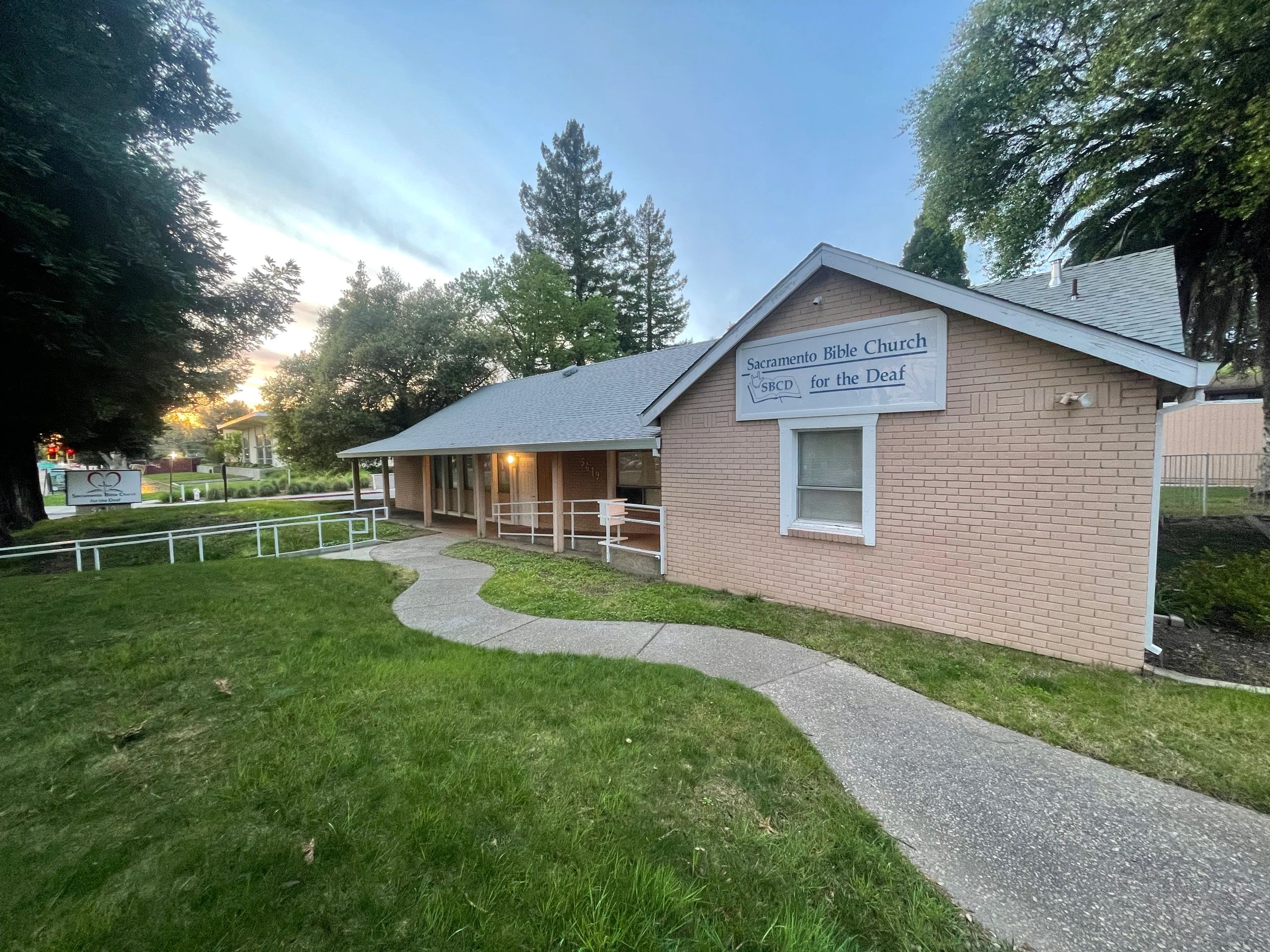 Sacramento Bible Church for the Deaf building with a curved sidewalk and green lawn.