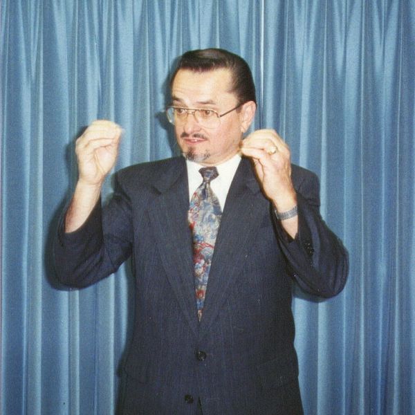 Man in suit gesturing with hands while speaking.