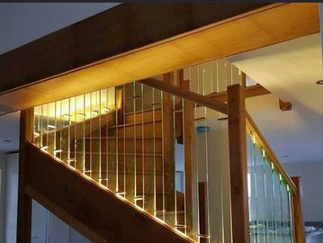 Wooden staircase with illuminated glass railings in a modern interior.