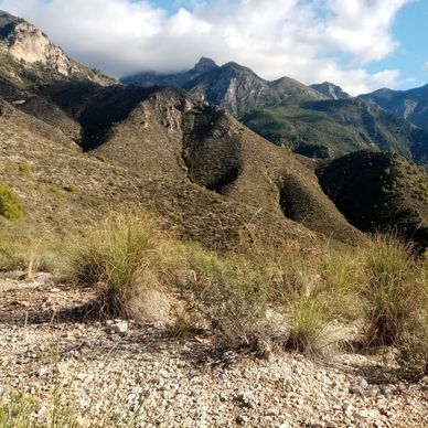 Montañas con vegetación y cielo parcialmente nublado.