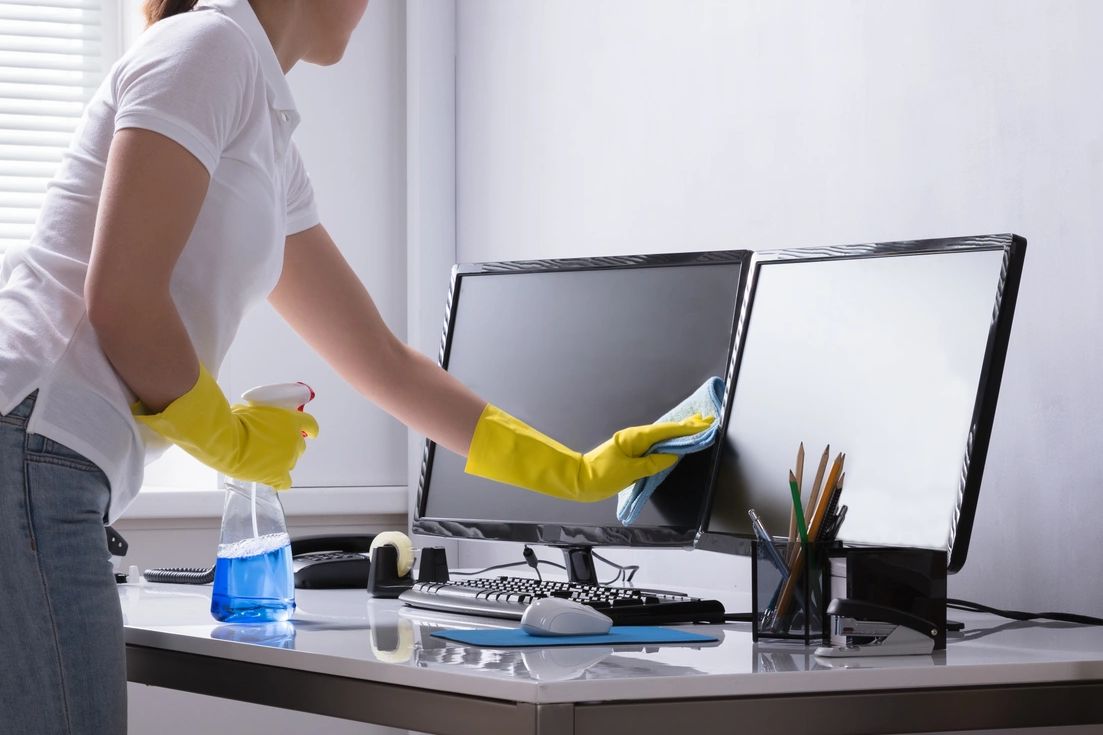 A young lady cleaning computer desks