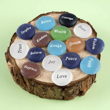 Colorful stones with positive words arranged on a wooden slab.