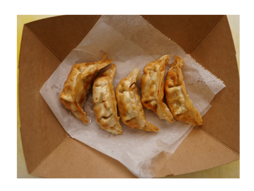 Five fried dumplings arranged in a takeout box on parchment paper.