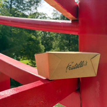 Takeout box from Fratelli's on a red outdoor railing.