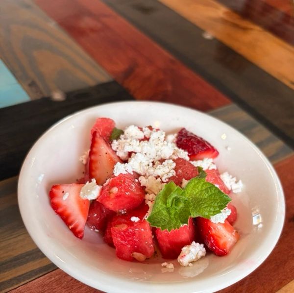 Fresh watermelon and strawberry salad with feta cheese and mint in a white bowl.