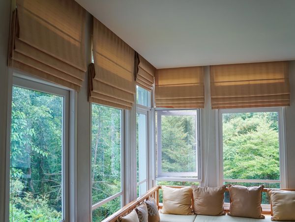 Window seat with pillows overlooking lush greenery.