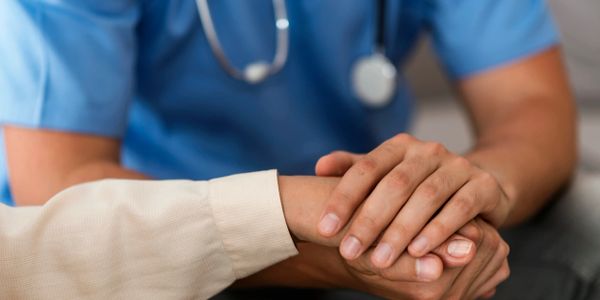 Doctor gently holding a patient's hand for comfort and support.