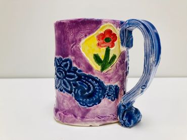 A blue and purple mug featuring swirls and red flowers.