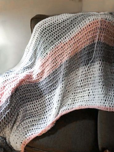 A blanket made from white, pink and grey yarn.
