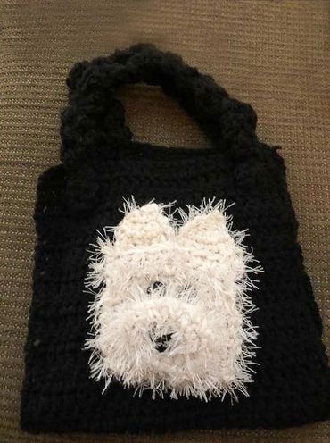A bag made from yarn with a white dog's face on the front.