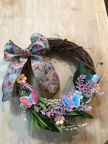 A spring wreath featuring flowers, ribbon and greenery.