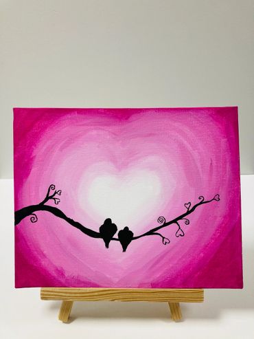 A painting of birds on a branch against a pink heart shaped background.