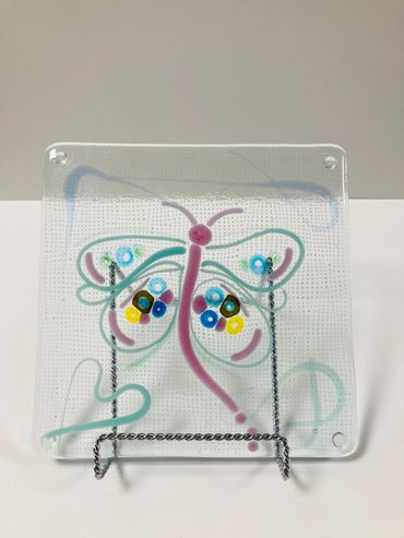 A fused glass square featuring a butterfly.