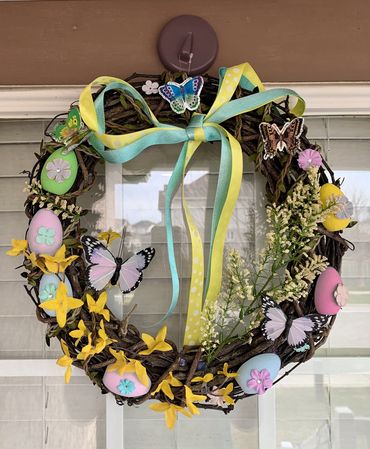 A spring wreath decorated with ribbon, eggs, butterflies and flowers.