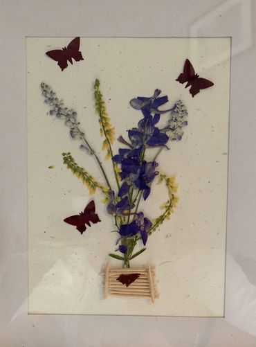A pressed flower piece featuring flowers and butterflies.