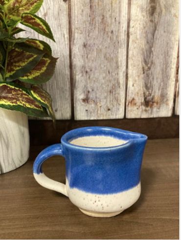 A blue and white short ceramic cream pitcher.