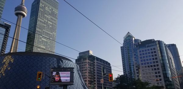 Cityscape with modern buildings and the CN Tower under a clear sky.