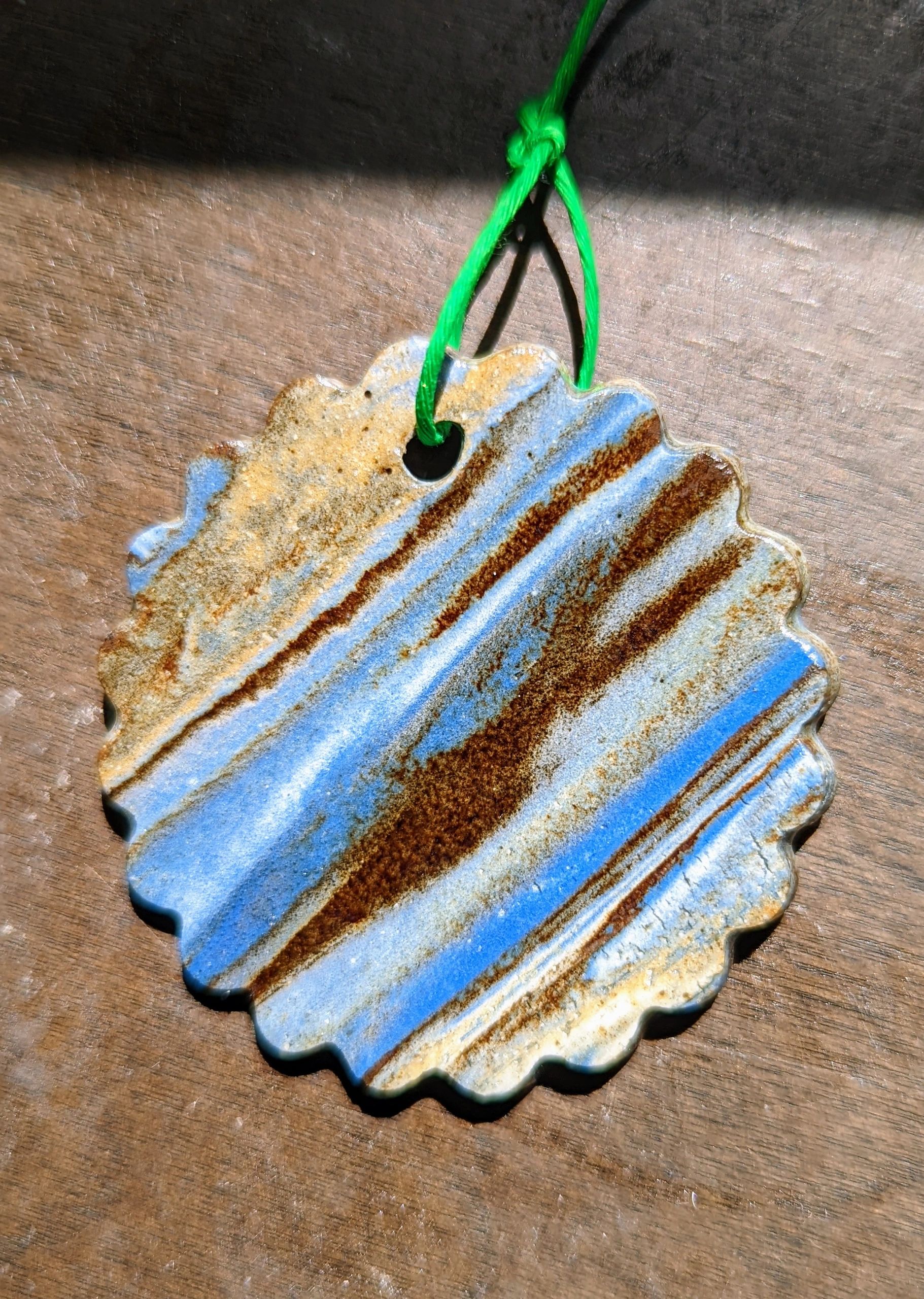 ornament, small flat round fluted edge flower shape with streaks of stained clays layered