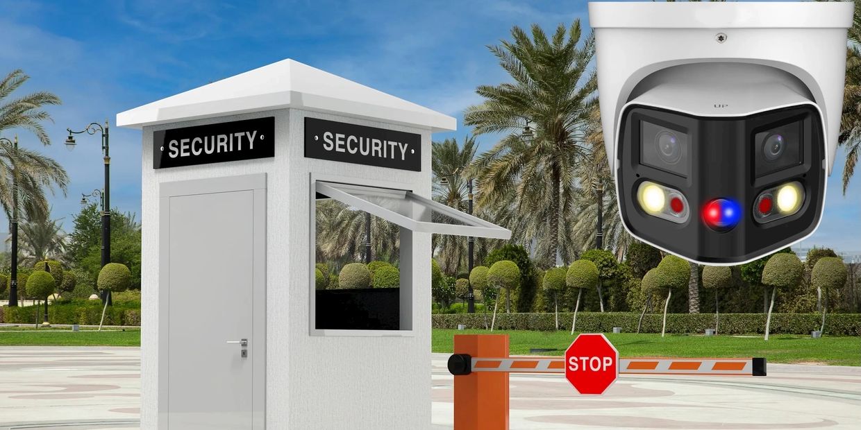 Modern security booth with surveillance camera and barrier gate in a landscaped area.