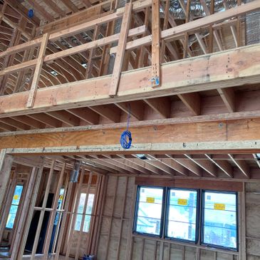 Interior of a wooden house under construction with exposed beams and wiring.