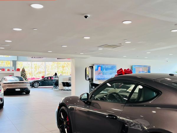 Luxury Porsche cars displayed inside a bright showroom with security branding.
