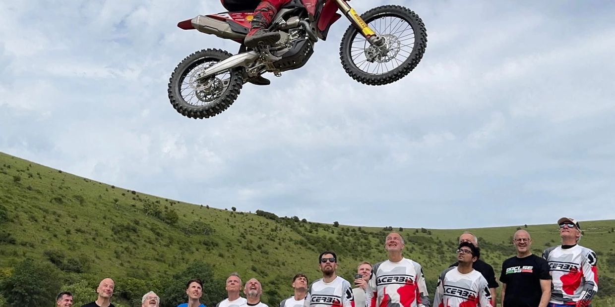 Dirt bike jumps high as crowd watches in awe outdoors.