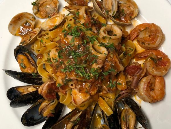 Seafood pasta dish with shrimp, mussels, and clams in a tomato-based sauce.