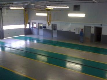 Empty indoor vehicle inspection lanes with a person near the wall.