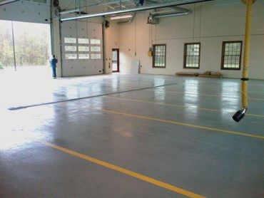 Empty indoor garage with yellow parking lines and open door.
