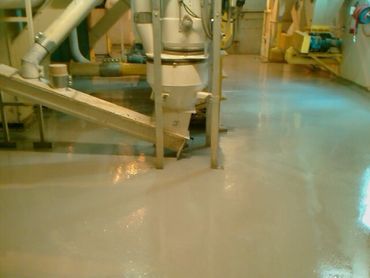 Industrial machinery on a shiny, wet factory floor.