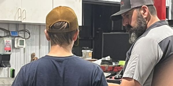 Two men talking in a workshop or garage.