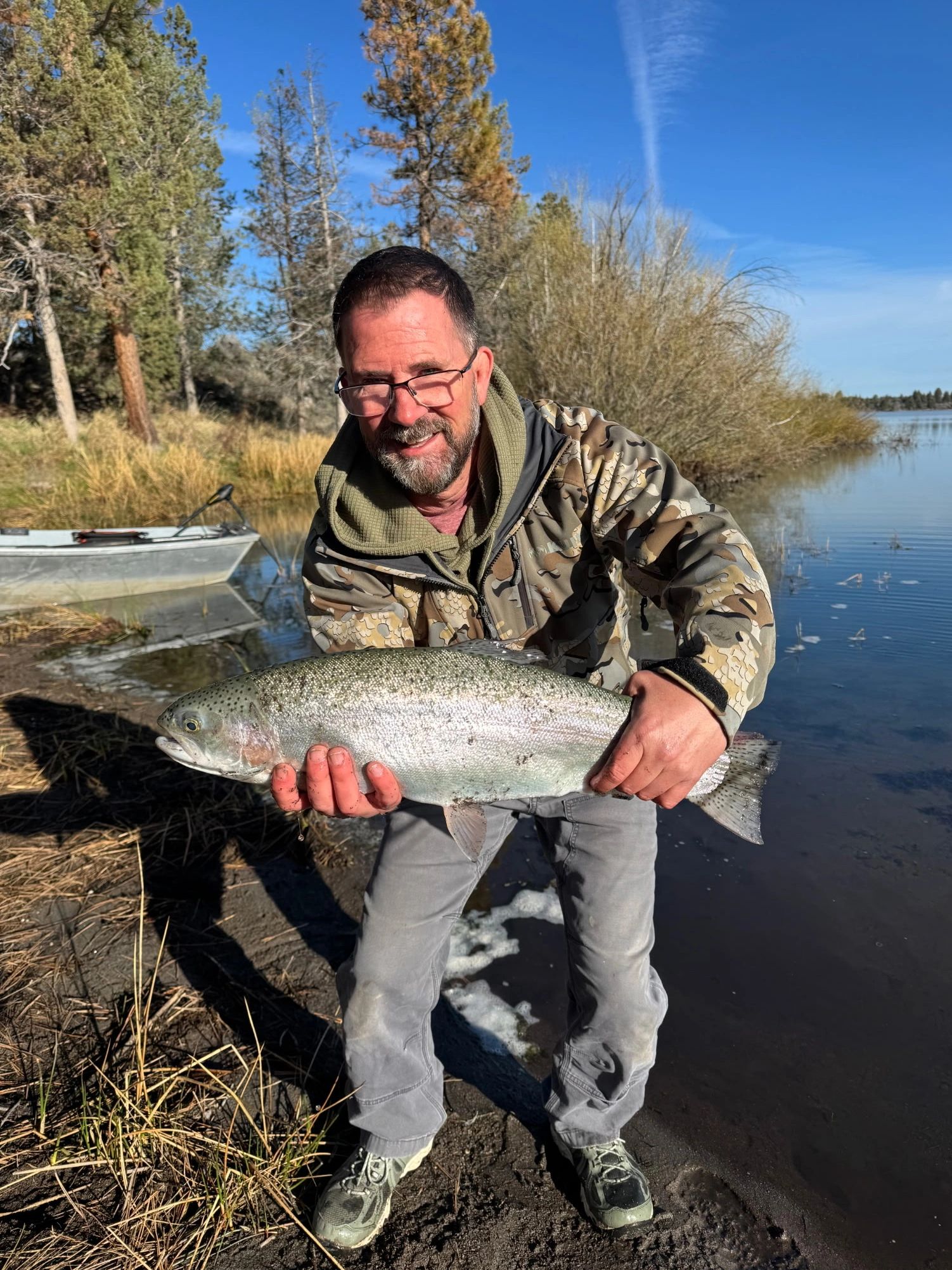 Man holding a large fish by the lake.