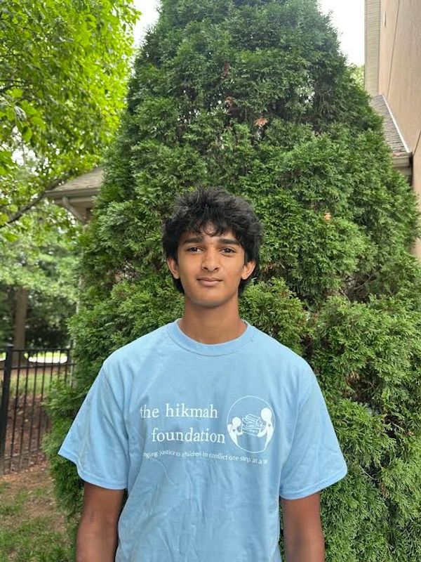 Young man standing outdoors in front of a tree.
