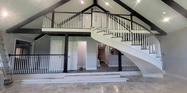 Modern interior with a curved staircase and vaulted ceiling beams.