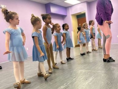 Young girls in blue ballet outfits lined up for dance class.
