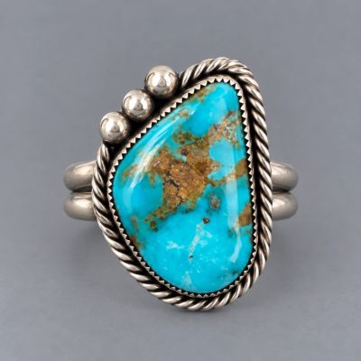 Handcrafted sterling silver ring with Kingman turquoise cabochon, twisted wire border and silver bea