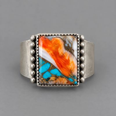 Silver ring with an orange, turquoise, and white stone.
