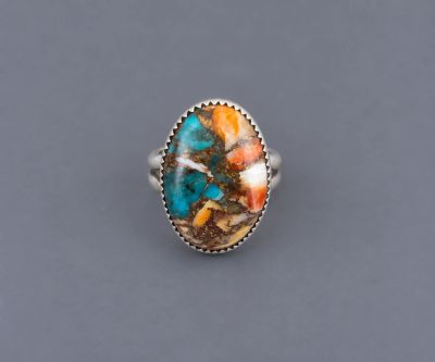 Sterling silver ring with an oval turquoise and spiny oyster composite stone in a serrated bezel.