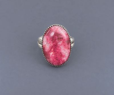 Oval pink thulite stone set in a serrated sterling silver bezel with a double half-round silver shan