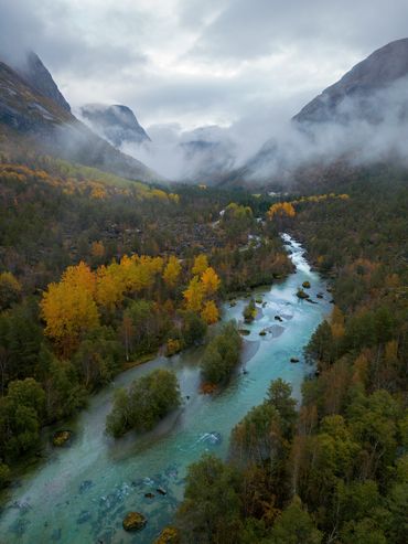 Glasklarer Fluss wird von Herbstfarben in Norwegen eingerahmt
