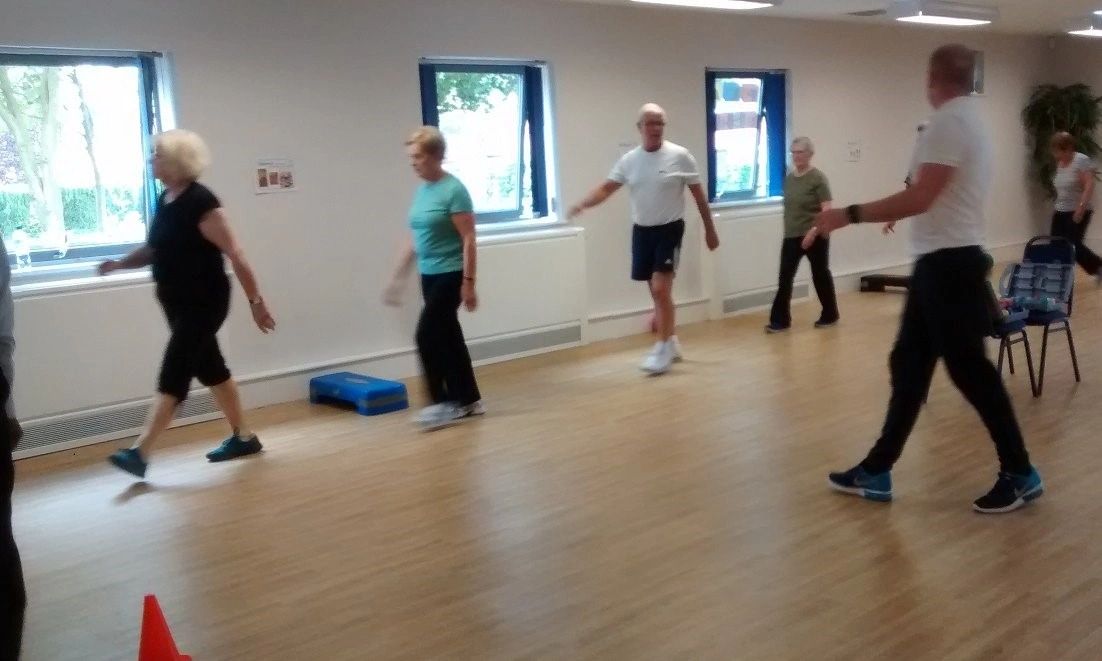 Exercise instructor leading a group, warming up, ready for a cardiac rehabilitation class.