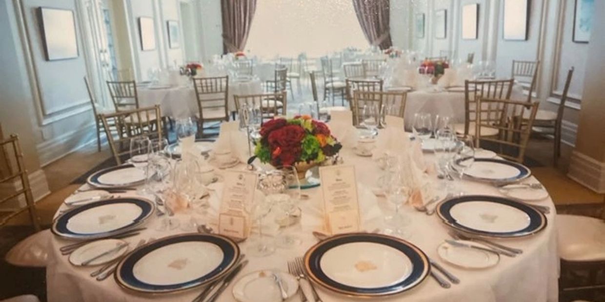 Elegant dining tables set for a formal event with floral centerpieces.