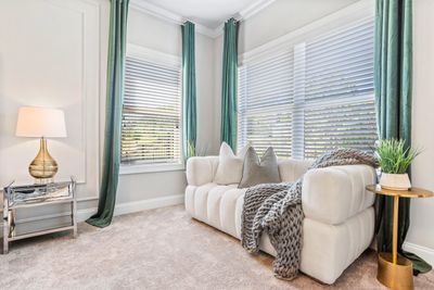 Bright and cozy seating nook with plush furnishing, rich green drapes, and stylish decor in Miami