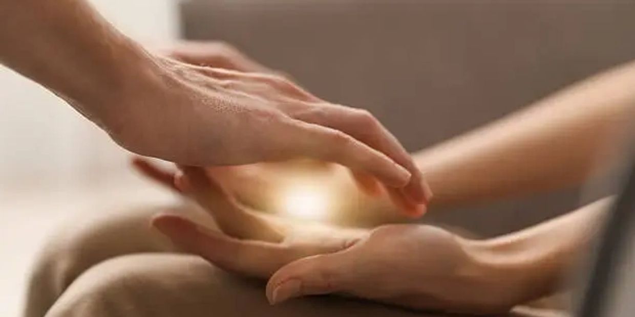 Hands gently touching with a soft glow between them.