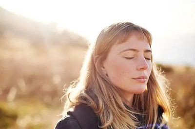 Woman with eyes closed enjoying sunlight.