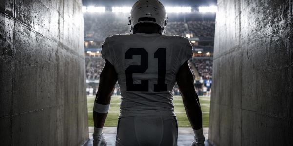 Football player walking out of tunnel to field.