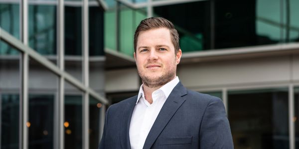 Confident man in suit standing outside a modern office building.
