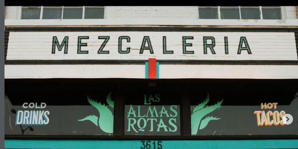 Front sign of Mezcaleria Las Almas Rotas offering cold drinks and hot tacos.